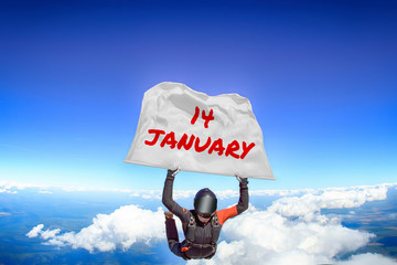 14 January. Parachutist flies a flag with date of January 14. Skydiver in black suit. Extreme as a way of life. 
