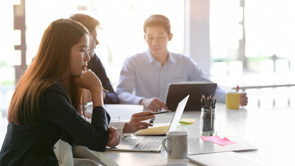 Cropped shot of business group focusing on their project while siting in simple meeting room