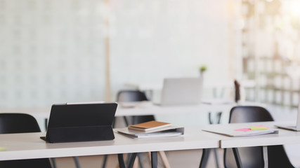 Cropped shot of office room with digital tablet and office supplies on white desk with blurred