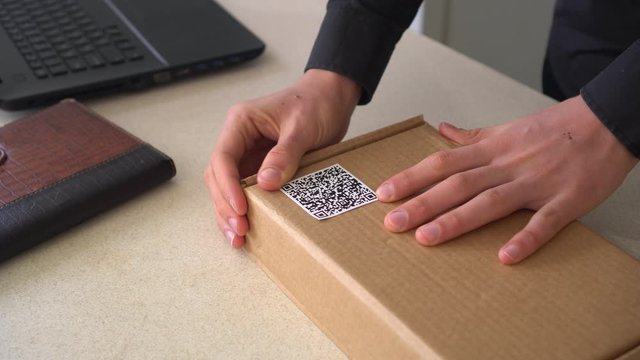 QR code technology. Small business. A Man pastes a Qr code on the package box. Delivery service. Online shop