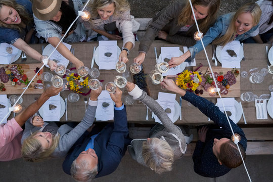 Overhead view friends toasting wine glasses at outdoor harvest dinner party