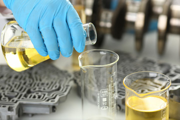 Male hands in protective gloves hold test tube in hands produces chemistry test of motor oil...