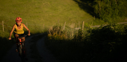 Naklejka premium Pretty, young woman biking on a mountain bike enjoying healthy active lifestyle outdoors in summer (shallow DOF)