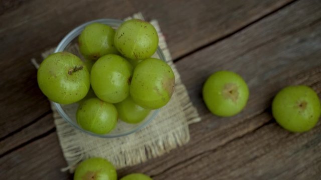 Fresh Indian gooseberry in glass bowl  on wooden board 
