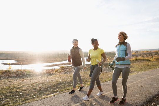 Women Power Walking Exercising On Sunny Path In Autumn Park