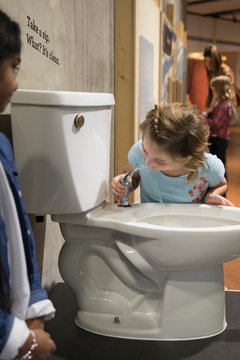 Girls drinking from toilet water fountain in science center