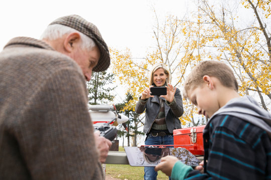 Senior man and grandson with model airplane remote control and digital tablet in park