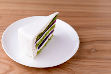 One piece of Japanese green tea matcha cake with white frosting and mint leaf served on white plate. Copy space.