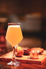 Glass of delicious light beer with grilled steak on wooden board served in restaurant. Food photography concept