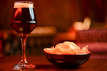 Glass of delicious dark beer with grilled steak on wooden board served in restaurant. Food photography concept
