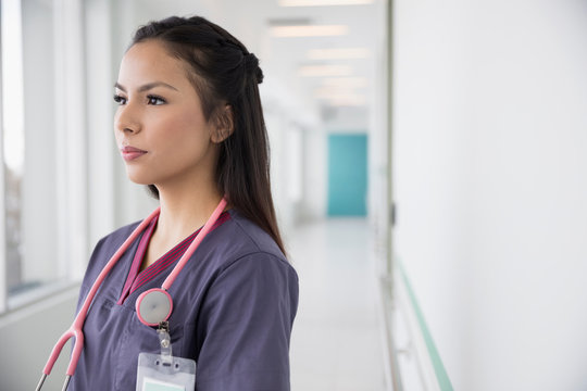 Portrait pensive female nurse looking away in clinic corridor
