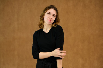 Studio portrait of a pretty blonde girl in a black T-shirt on a beige background with bright emotions. A universal concept, the picture is suitable for any topic.