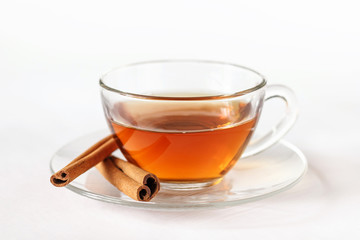 Glass cup of tea with cinnamon sticks. White background. Isolated. Close up. Hot spiced cinnamon tea.