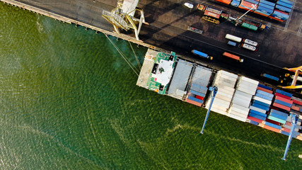 Container ship alongside at container terminal has loading and discharging operations by gantry...