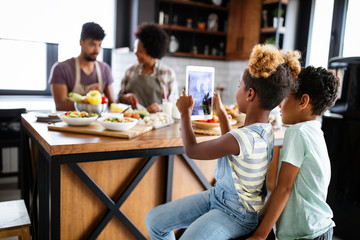 Happy african american family preparing healthy food together in kitchen