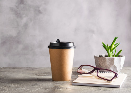 Disposable paper cup with coffee drink or tea notepad glasses on the desktop. Concept business lunch break zero waste.