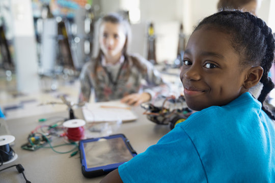Portrait smiling pre-adolescent girl assembling robotics in classroom