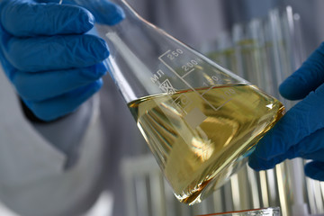Male hand hold yellow liquid in test tube. Conveyor line production household cleaning products...