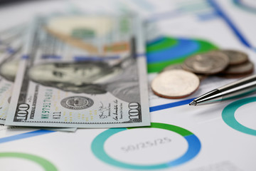 Silver pen lying on desk cash dollar plots in home office setting. Calculation of family expenses social income population freelance irs situation growth research concept