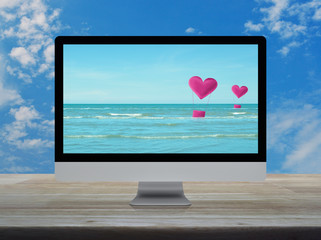 Pink fabric heart love air balloon on tropical sea with desktop modern computer monitor screen on wooden table over blue sky with white clouds, Business internet dating online, Valentines day concept