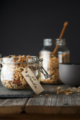 Organic homemade granola cereal with oats, nuts and dried berries. Muesli in a glass jar on the...