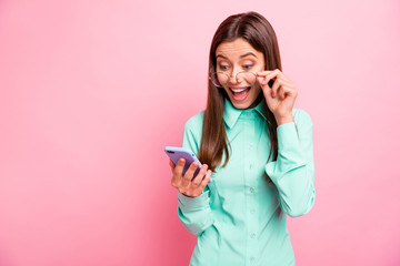 Fototapeta premium Photo of crazy lady hold telephone hands read followers comments like positive reactions open mouth gladness wear specs turquoise shirt isolated pink color background