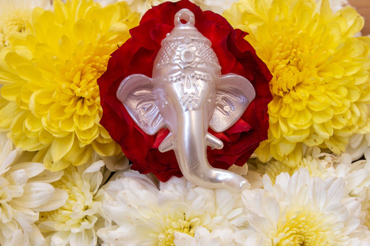 Face of lord Ganesha placed over beautiful rose and chrysanthemum flowers. Use for religious concepts.