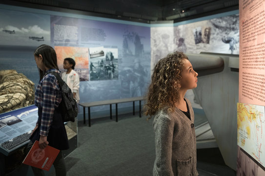 Curious girl student looking at exhibit on field trip in war museum