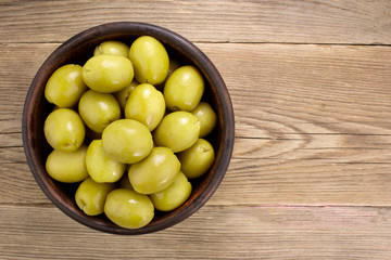  Green olives  in bowl on wooden table