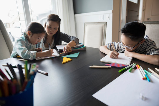 Mother helping daughter with homework at table