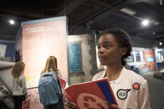 Curious African American girl student with notebook on field trip in war museum