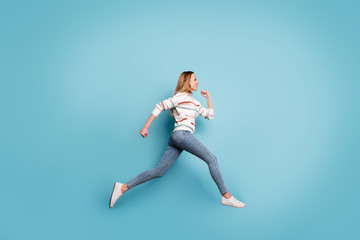Fototapeta na wymiar Side profile full length body size photo of cheerful positive pretty sweet girlfriend smiling toothily in jeans denim running jumping isolated pastel blue color background