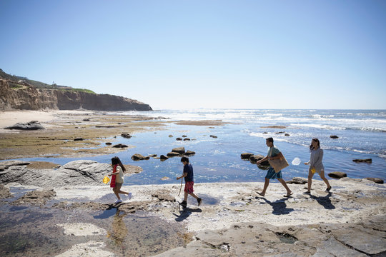 Latino family walking on craggy sunny beach