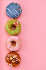 Sweet donuts of different colors, on a pink background. Copy space, blue and pink backgrounds
