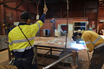 Miner welder supervisor standing supervising a arc welding at the construction fabrication site...