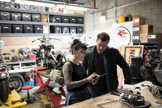 Motorcycle mechanics using digital tablet in auto repair shop