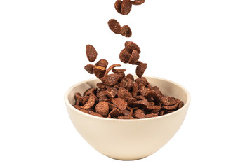 Chocolate corn flakes falling to the white bowl isolated on white. Motion.