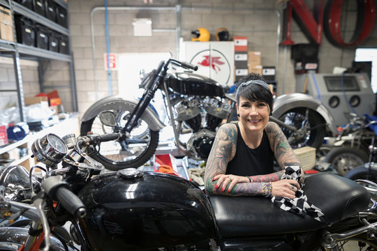 Portrait confident female motorcycle mechanic with tattoos in auto repair shop