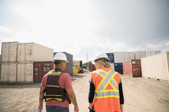 Workers walking in sunny industrial container yard
