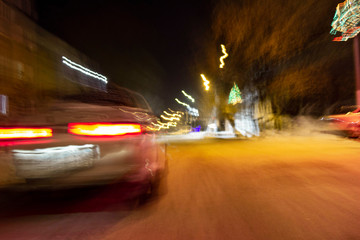 Obraz premium the car is driving at high speed on the night street of the city, blurred image along the lines of the road with zoom