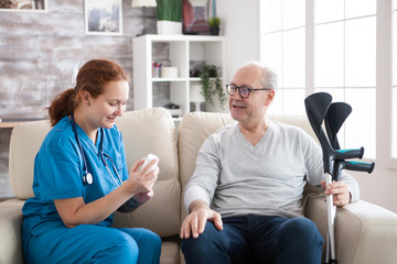Fototapeta premium Female doctor in nursing home sitting on couch holding pills