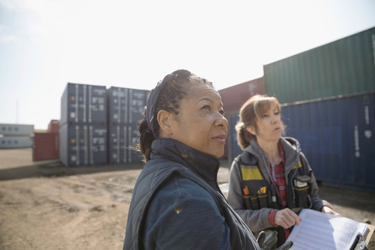 Female workers looking away in industrial container yard