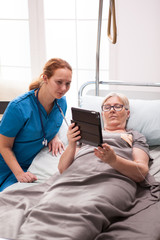 Fototapeta premium Elderly age woman and female doctor reading on tablet computer