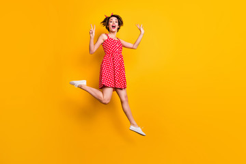 Full body photo of cheerful enthusiastic girl jump enjoy spring free time holiday make v-sign wear...