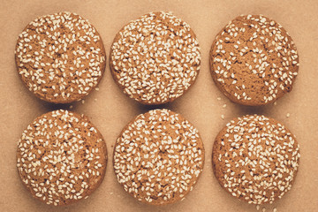 Oatmeal cookies on baking paper. Handmade bakery with sesame seeds. Brown background. A group of biscuits.