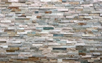 Stone cladding wall made of  striped stacked slabs of natural multicolor rocks. Panels for...