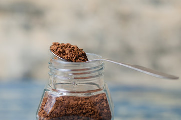 Spoon with instant coffee over the can closeup. Coffee granules macro.