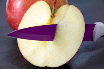 Media manzana cortada  y atravesada con un cuchillo 