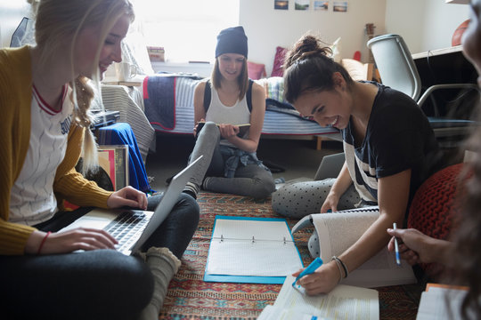 Female College Students Studying On Floor In Dorm Room