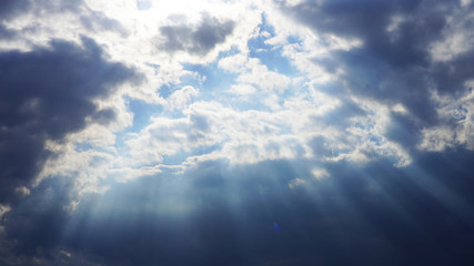 dramatic sky, dark clouds on a blue sky, the rays of the sun pass through the clouds in lines. glow...